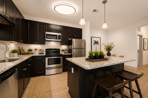 Millennium Apartments' kitchen with a granite island and stainless steel appliances